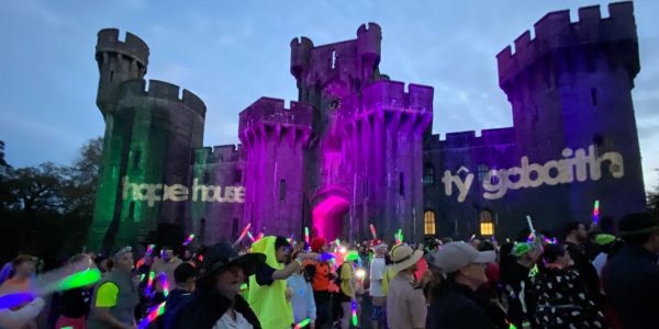 a castle lit up with runners and glowsticks and ty gobaith logo