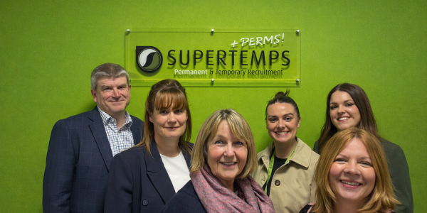6 supertemps employees smiling for the camera on green background with Supertemps logo